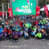 Fotografía grupal de cientos de ciclistas y asistentes al Festival de Verano, reunidos al aire libre frente a un escenario con una pantalla que anuncia la edición 29 del Festival de Verano.