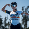 Gabriel Rueda, patinadora bogotana, posa con uniforme de la Liga de Patinaje de Bogotá y casco deportivo en una pista al aire libre, señalando el logo de Bogotá en la camiseta, con árboles desenfocados al fondo y cielo despejado.
