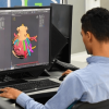Foto que muestra dos personas trabajando frente a un computador 