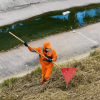Foto que muestra una persona con el uniforme de Aguas Bogotá limpiando un canal de agua 
