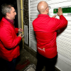 Foto que muestra dos hombres colocando un aviso de sellamiento en un local comercial 