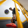 Messedinho realizando dominio de balón de fútbol en una escalera interior, vista desde abajo entre barandas amarillas que enmarcan la escena.