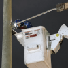 Foto que muestra una persona realizando labores de mantenimiento en un poste de luz 