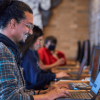 Imagen de un hombre sonriendo al frente de un computador portátil 