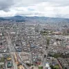 Vista panorámica de Bogotá con edificaciones, vías principales y los cerros orientales al fondo bajo un cielo nublado.