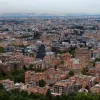 Vista panorámica de Bogotá con numerosos edificios residenciales y comerciales que se extienden por la ciudad, observados desde una zona elevada con vegetación en primer plano.