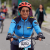 Participante de la Ciclovía de Bogotá se desplaza en bicicleta por una vía habilitada para la actividad. Lleva casco rojo, gafas y una camiseta deportiva azul con el número 0382 en la parte frontal.