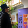 Imagen de un hombre vestido de mago observando en un cartel la información del Quinto Salón de Artistas a la KY 2026.