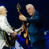 Imagen de dos hombres mayores tocan guitarra en un escenario.
