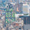 Vista panorámica del centro de Bogotá con edificios de diferentes alturas, una torre de fachada verde y amarilla en primer plano, vías urbanas y construcciones residenciales y comerciales densamente agrupadas.