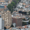 Vista panorámica de Bogotá con edificios residenciales y comerciales de diferentes alturas en primer plano, y los Cerros Orientales en un día nublado.