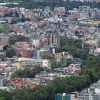 Vista panorámica de sectores residenciales y edificaciones de Bogotá, con viviendas de distintos tamaños distribuidas en una zona urbana rodeada de áreas verdes.