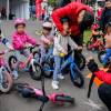 Niños y niñas de primera infancia participan en una actividad de push bike con bicicletas de equilibrio y cascos de protección en un espacio al aire libre en Bogotá.