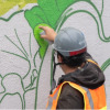 Imagen de un hombre dando la espalda que pinta un graffiti.