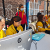 Foto que muestra hombres y mujeres trabajando frente a un computador