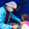 Foto que muestra una persona con gorro y tapabocas colocando una vacuna 