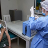 Imagen de una enfermera aplicando una vacuna a una mujer mayor que usa tapabocas