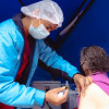 Foto que muestra un enfermero colocando una vacuna en un brazo a una mujer mayor.