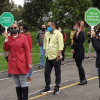 Grupo de personas participando en una actividad de evacuación al aire libre, posiblemente un simulacro de emergencia. Algunas llevan tapabocas y sostienen señales con los nombres de diferentes dependencias institucionales para el Simulacro Bogotá 2026.
