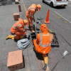 Foto que muestra tres personas con el uniforme de Aguas Bogotá limpiando un sumidero 