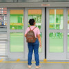 Foto de una mujer en una estación de TransMilenio frente a una de las puertas automáticas.