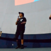 Imagen de dos hombres vestidos de negro en una tarima, uno de ellos no tiene una pierna. Al lado hay una mujer traductora de lenguaje de señas.