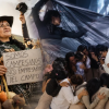 Imgen de la puesta en escena donde se ven varias personas en un circulo y de fondo se ve una mujer campesina y varias hortalizas.