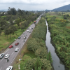 Vista aérea de la Autopista Norte de Bogotá con tránsito vehicular junto a un canal de agua y amplias zonas verdes que serán atendidas por el PMU.
