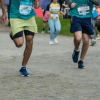 Primer plano de las piernas de varios corredores mientras participan en una carrera atlética sobre una vía pavimentada.