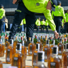 Foto de policías exponiendo en el piso botellas incautadas.