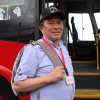 Persona con gorra negra, camisa azul claro y morral gris se encuentra junto a la puerta abierta de un bus rojo del sistema de transporte. En el costado del vehículo se observa la identificación “E752” y el nombre “Gmóvil S.A.S.”, mientras que el interior del autobús muestra pasamanos y escalones amarillos.