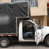 Camioneta del programa Foncarga de Bogotá estacionada con la puerta del conductor abierta y un módulo cubierto instalado en la parte trasera, frente a edificaciones urbanas.