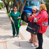 Foto de una mujer con discapacidad visual utilizando un bastón blanco con punta roja en una acera de Bogotá, mientras dos mujeres conversan a su lado.