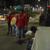 Operativo nocturno de atención social en un corredor vial, con personal de entidades distritales y varias personas junto a enseres y objetos retirados del espacio público.