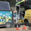 Vehículo de la Unidad Móvil de Control Ambiental de la CAR Cundinamarca, equipado con panel solar en el techo, conectado a un bus de transporte mediante cables de medición.