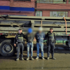 Dos capturados en medio de dos Policías. Detrás está el camión con los 11 rieles incautados.