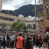 Personas reunidas en una plaza del centro de Bogotá durante una actividad al aire libre. En primer plano se observan participantes y personal con chalecos naranjas, mientras al fondo se distinguen edificaciones históricas y los cerros orientales.