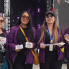 Cuatro mujeres con chaqueta morada de la Secretaría de la Mujer en un concierto.