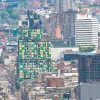 Vista panorámica del centro de Bogotá con edificios de diferentes alturas; en primer plano, una fachada intervenida con paneles verdes y amarillos entre construcciones urbanas.