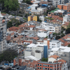 Vista aérea de un sector residencial y comercial de Bogotá, con edificios de mediana y gran altura, viviendas de teja roja y áreas arborizadas.