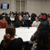 Foto que muestra estudiantes sentados en una mesa hablando 