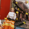 Imagen de una mujer vestida con traje típico colombiano de color amarillo, de fondo se ven mariposas amarillas.
