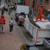 Foto que muestra un carro recolector de basura y personas caminando en la calle 