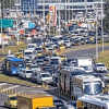 Alta congestión vehicular en avenida El Dorado de Bogotá con filas de carros, buses, camiones y motocicletas avanzando lentamente entre varios carriles. Se observan separadores viales, señalización y tránsito denso en ambos sentidos.