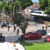 Vista general de una intersección vial en Bogotá con vehículos particulares, motocicletas y un camión detenidos. En un costado de la vía se observa un grupo de personas reunidas y presencia de operarios, mientras el tráfico avanza lentamente.