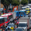 Tráfico congestionado sobre una avenida de Bogotá, con buses de TransMilenio, vehículos particulares, camiones y numerosas motocicletas ocupando varios carriles.
