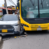 Primer plano de una colisión entre un bus articulado amarillo de TransMilenio y un vehículo particular gris en una vía de Bogotá