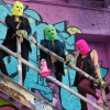 Imagen de tres mujeres con capcuhas de colores y un megáfono 