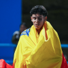 Deportista envuelto en bandera de Bogotá durante una competencia deportiva, con parte de una pista azul visible al fondo.