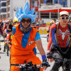 Personas disfrazadas de personajes de anime y superhéroes participan en una jornada de Recreovía en Bogotá, mientras recorren una avenida en bicicleta junto a decenas de ciclistas.